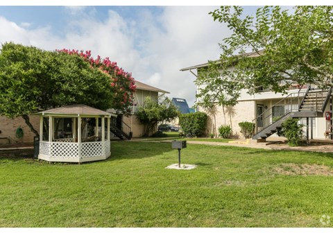 a gazebo in the middle of a yard in front of a house