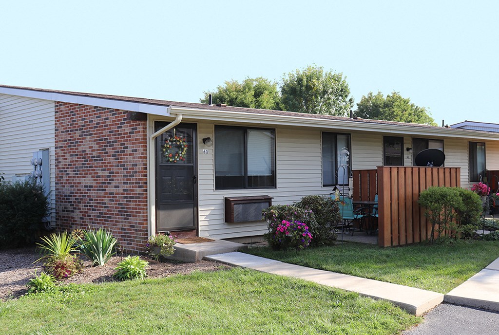 a small white house with a porch and a lawn