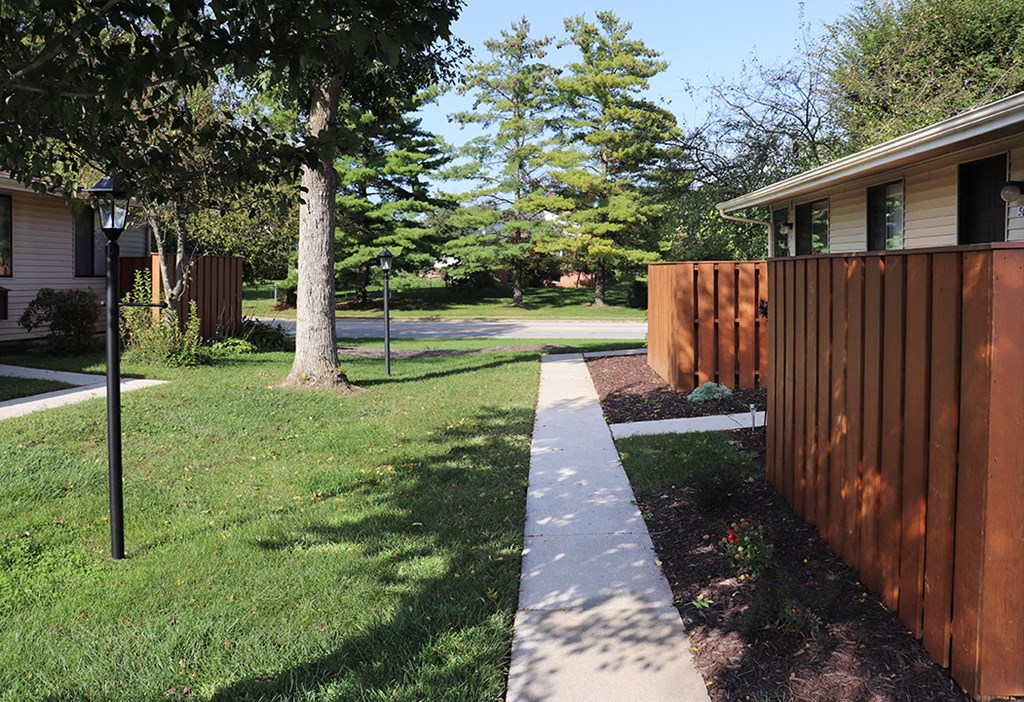 a sidewalk in front of a wooden fence
