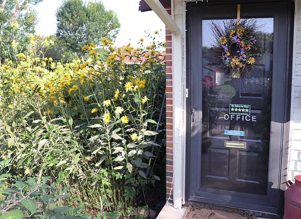 the front door of the office with flowers in the garden