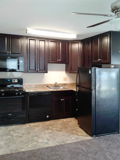 a kitchen with black appliances and dark wood cabinets