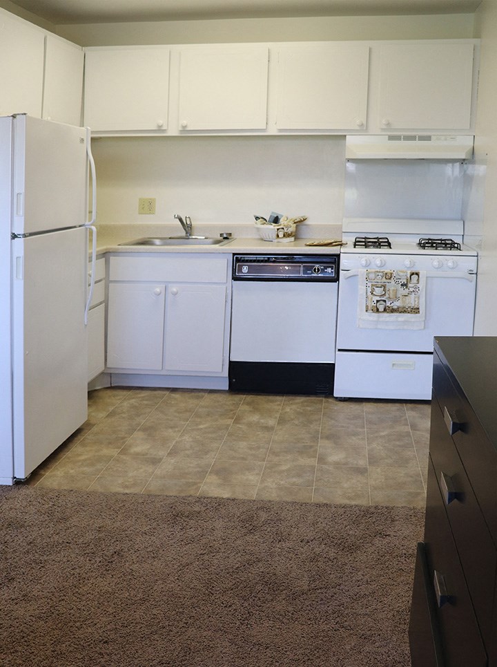 an empty kitchen with white appliances and white cabinets