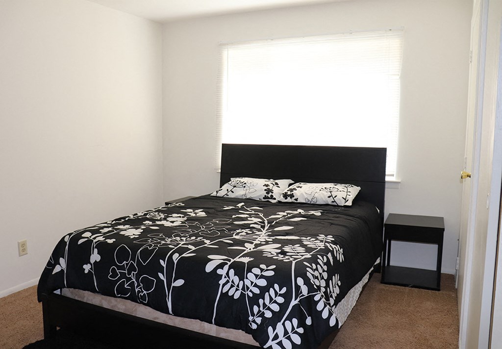 a bedroom with a black and white bed and a window