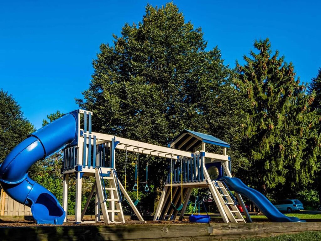 a playground with a blue slide and a wooden playset