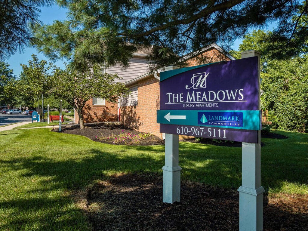 a sign for the meadows with a building in the background