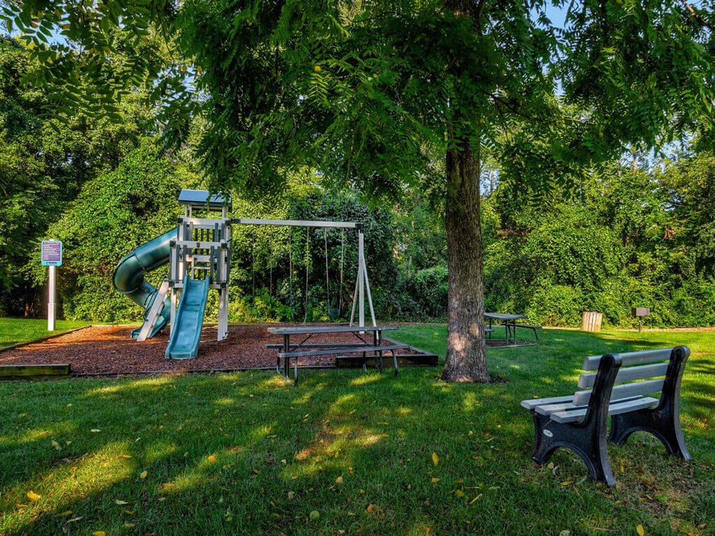 a playground with a swing set and a bench in a park