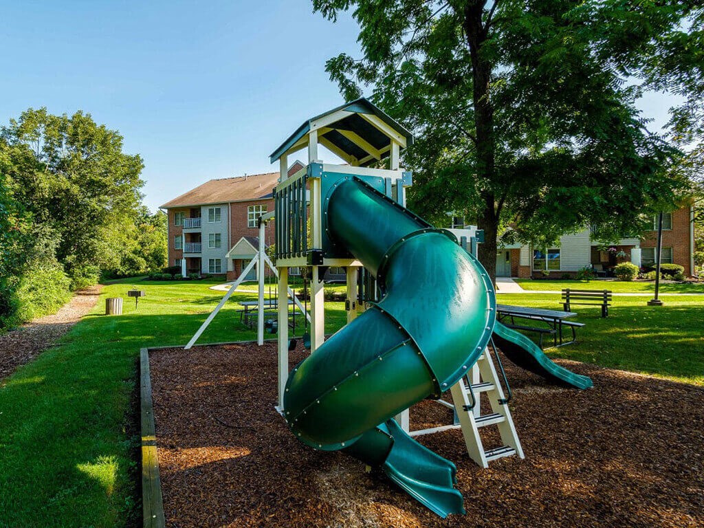 a playground with a green slide in a park