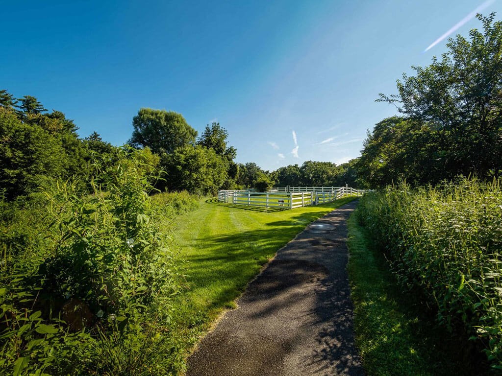 a dirt road with a fence on the side of a field