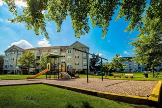 a playground with a swing set in front of an apartment building