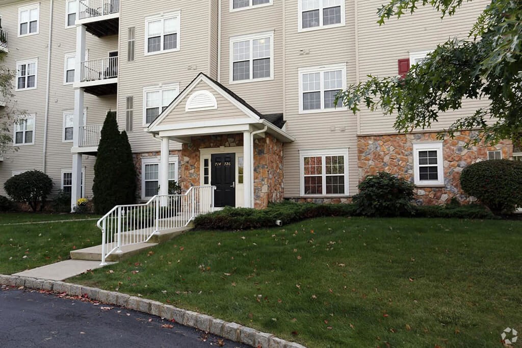 the front of an apartment building with a porch and stairs