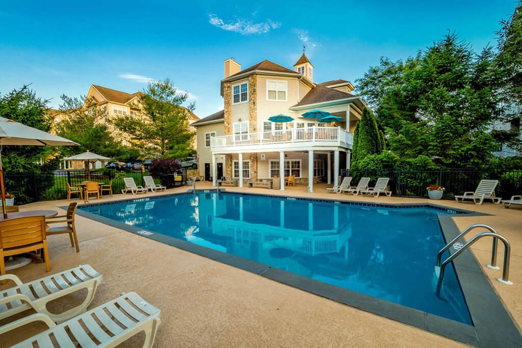 a large swimming pool in front of a house with a large porch
