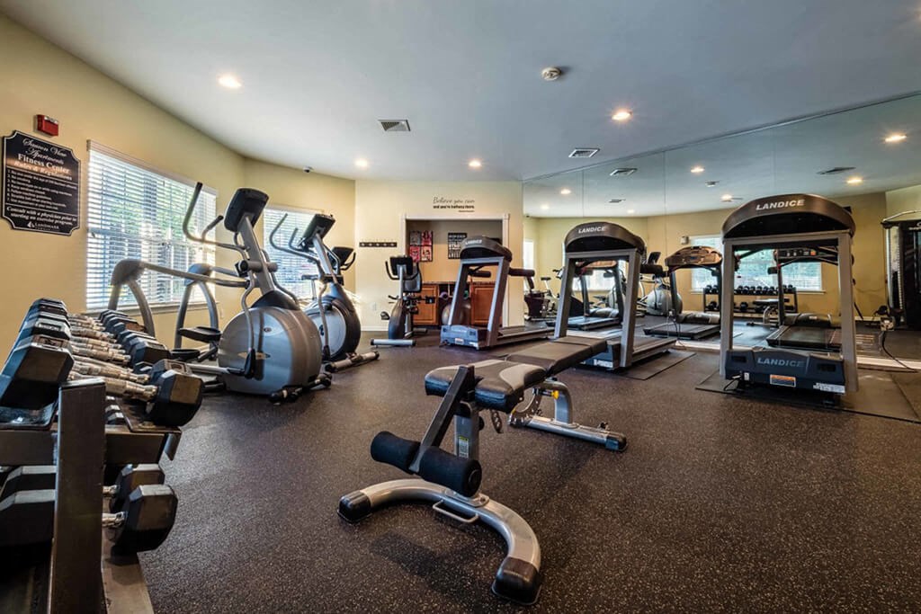 a gym with cardio machines and weights on the floor