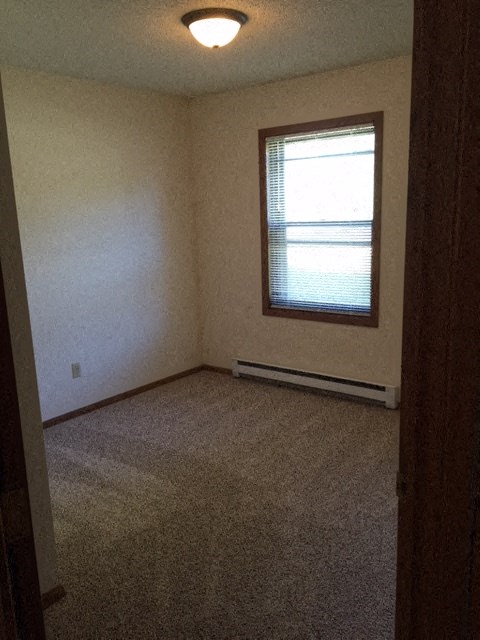 an empty room with a window and a carpet