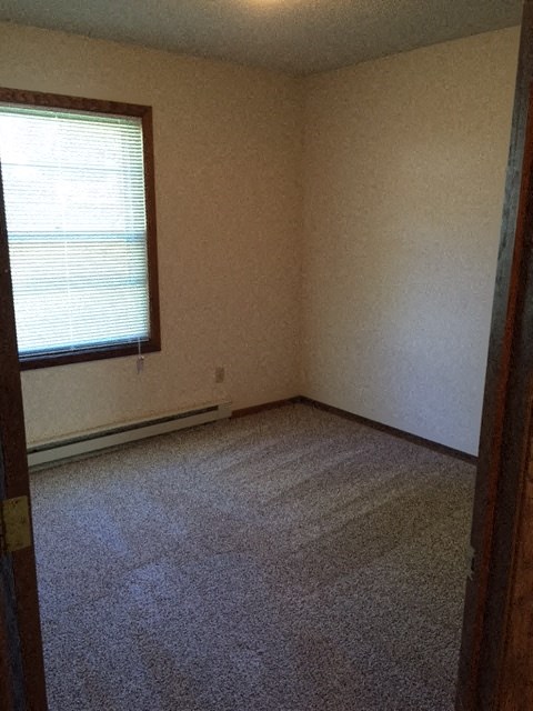 an empty room with a window and carpet
