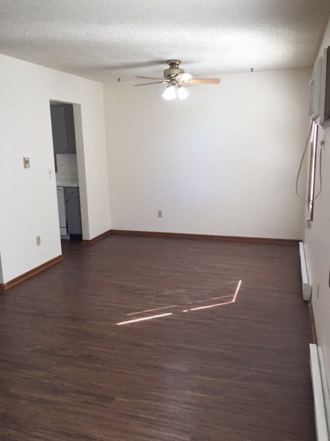 an empty living room with wood floors and a ceiling fan