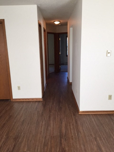 an empty hallway with white walls and wood flooring