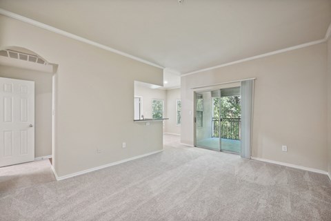 a living room with a door to a balcony and a carpeted floor