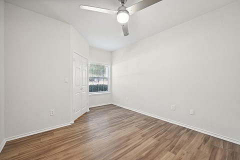 an empty living room with white walls and a ceiling fan