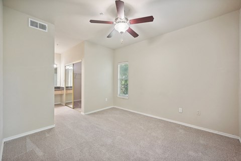 an empty living room with a ceiling fan