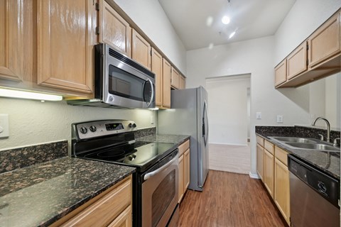 a kitchen with granite counter tops and wooden cabinets and stainless steel appliances