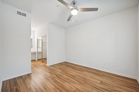 an empty living room with wood flooring and a ceiling fan