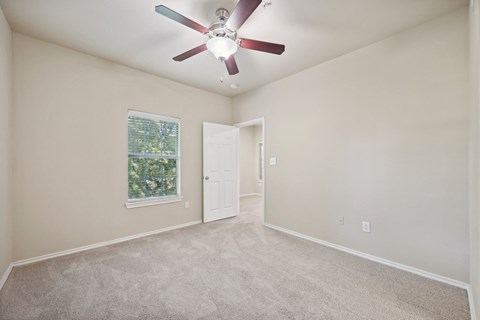 an empty living room with a ceiling fan and a window