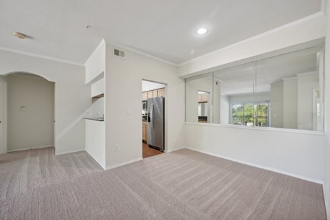 the living room and kitchen of a new home with white walls and carpet