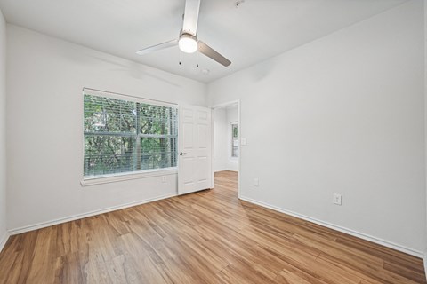 the living room and dining room of an empty house with wood floors and a window