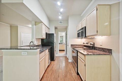 an empty kitchen with white cabinets and black counter tops