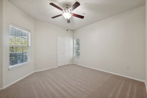 an empty living room with a ceiling fan and a window