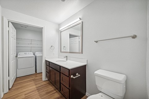 a bathroom with a toilet sink and mirror and a laundry room