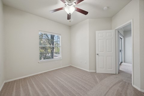 an empty living room with a ceiling fan and a window