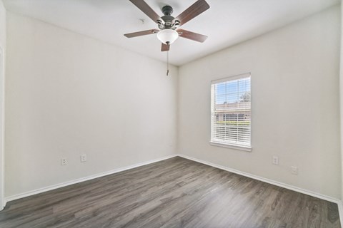 an empty living room with a ceiling fan and a window