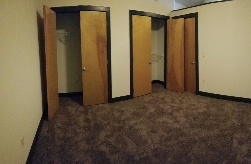 a room with a carpeted floor and a row of closet doors