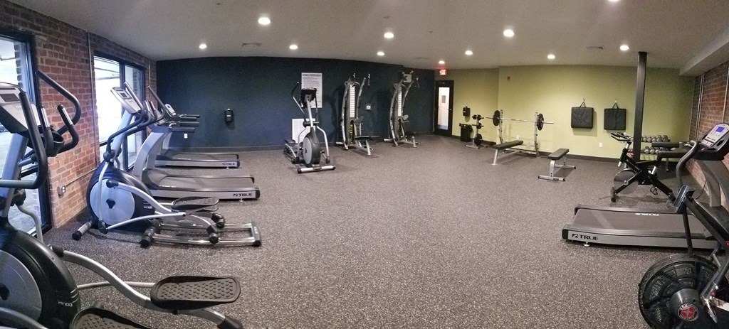 a gym with cardio equipment and weights on the floor