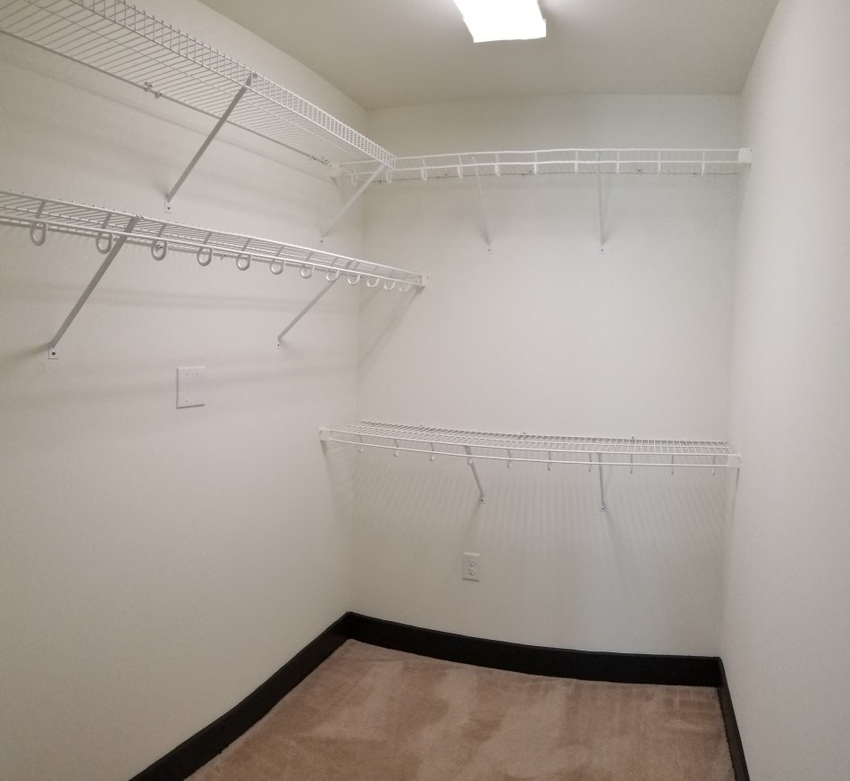 a walk in closet with white walls and a hanging rack