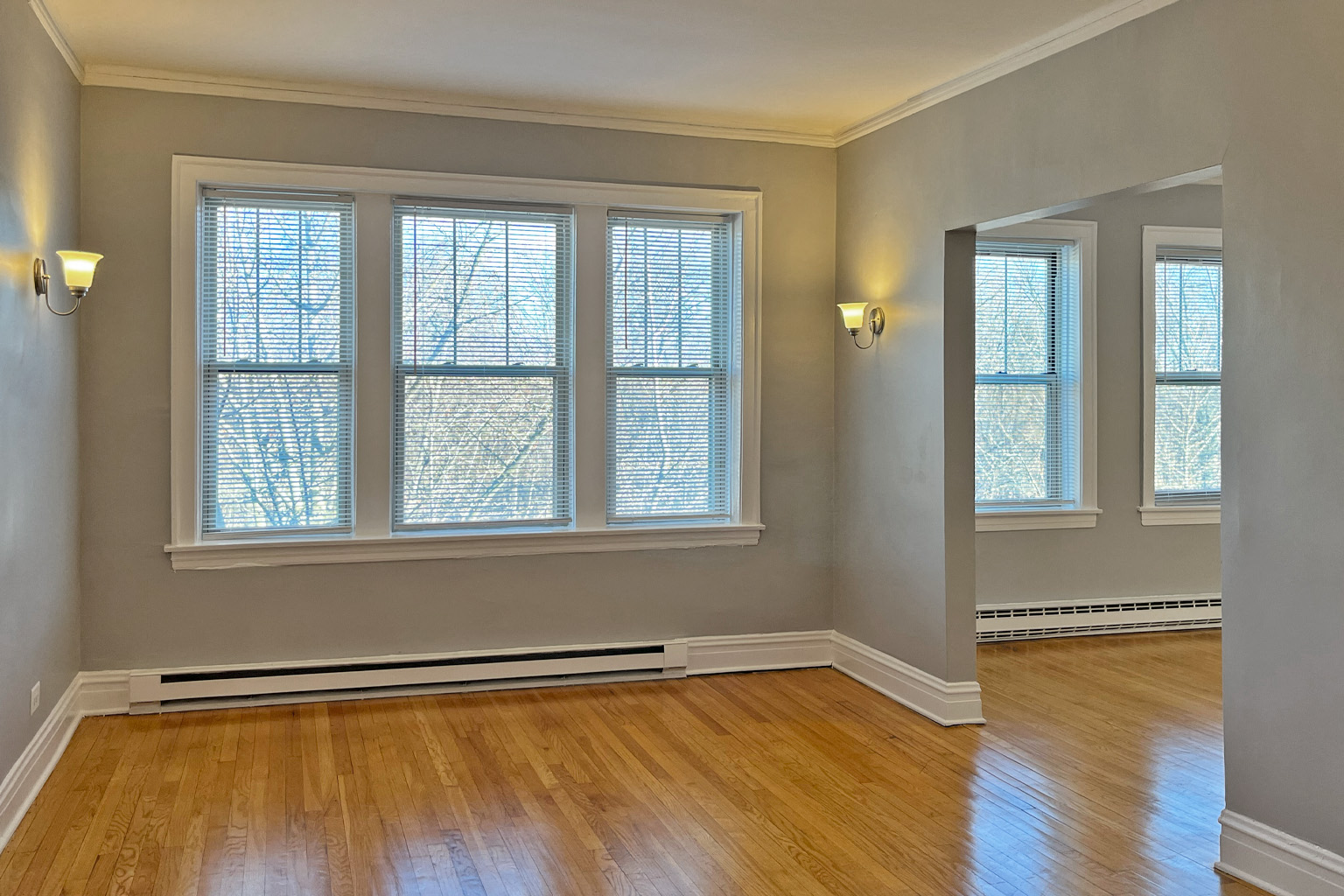 A room with wooden floors and three windows.
