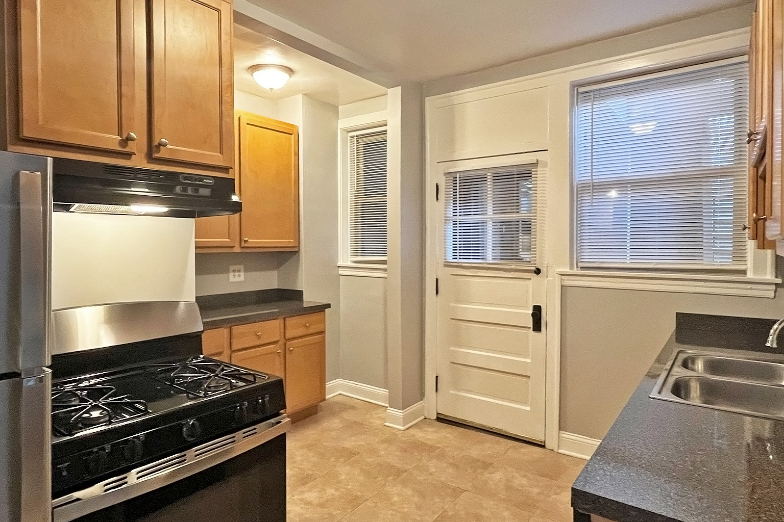 A kitchen with a stove, sink, and cabinets.