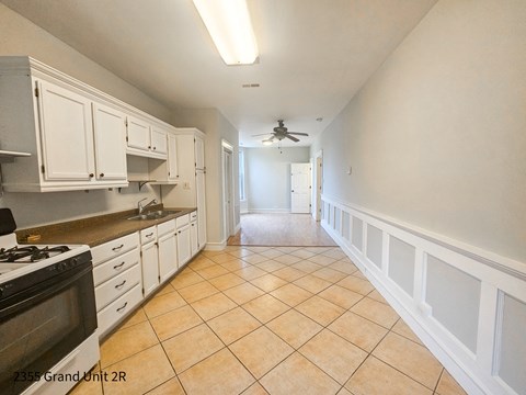 a kitchen with white cabinets and tiled floors and a ceiling fan