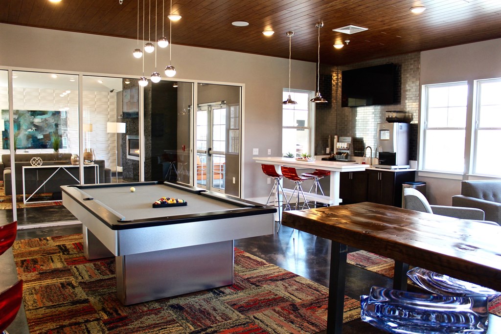 an open living room with a pool table and a kitchen with a bar