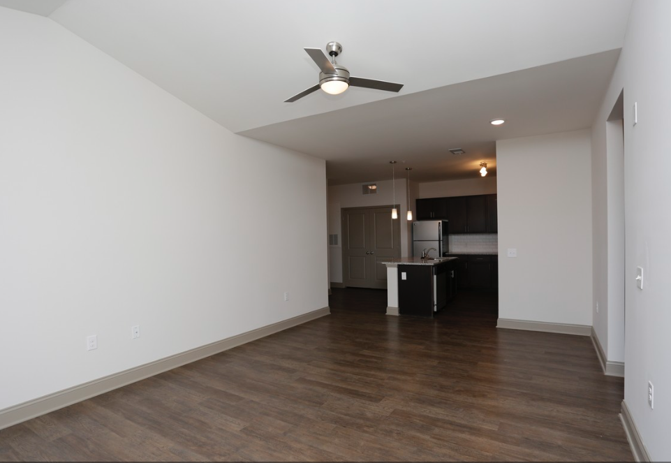 an empty living room with white walls and a ceiling fan