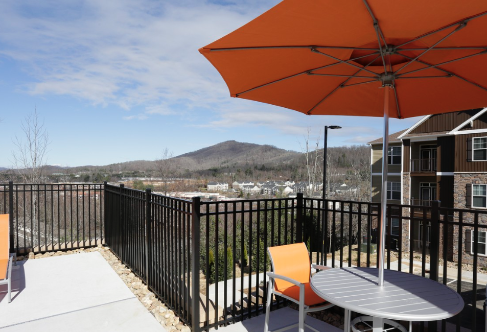 a patio with a table and chairs and an orange umbrella