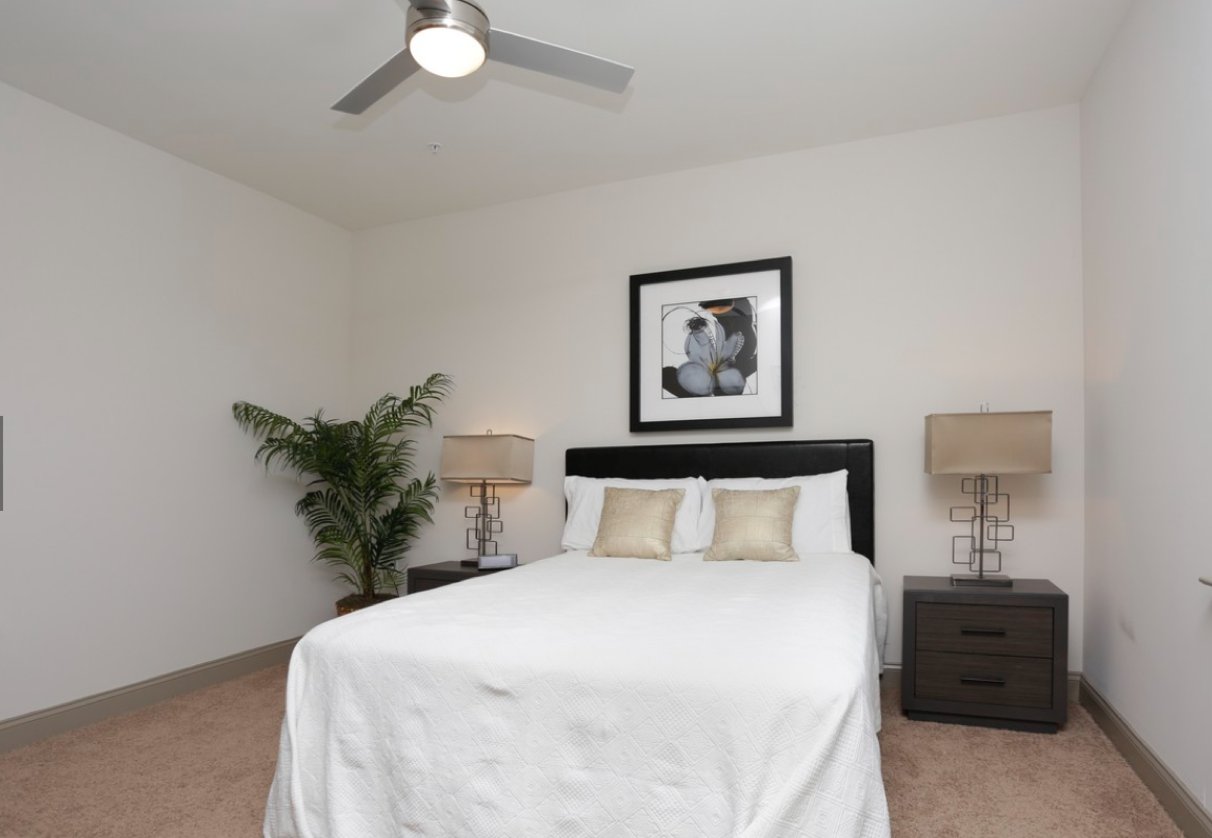 a bedroom with a white bed and a ceiling fan