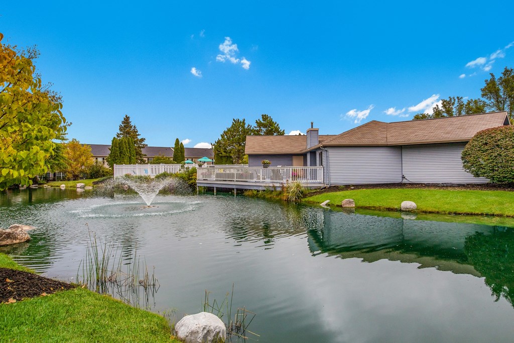 a pond with a fountain in front of a house