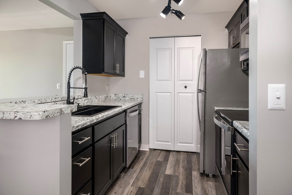 an empty kitchen with black cabinets and a stainless steel refrigerator