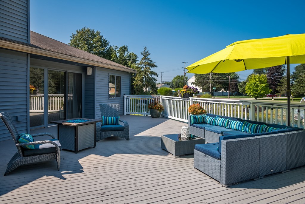 a patio with furniture and a yellow umbrella on a house