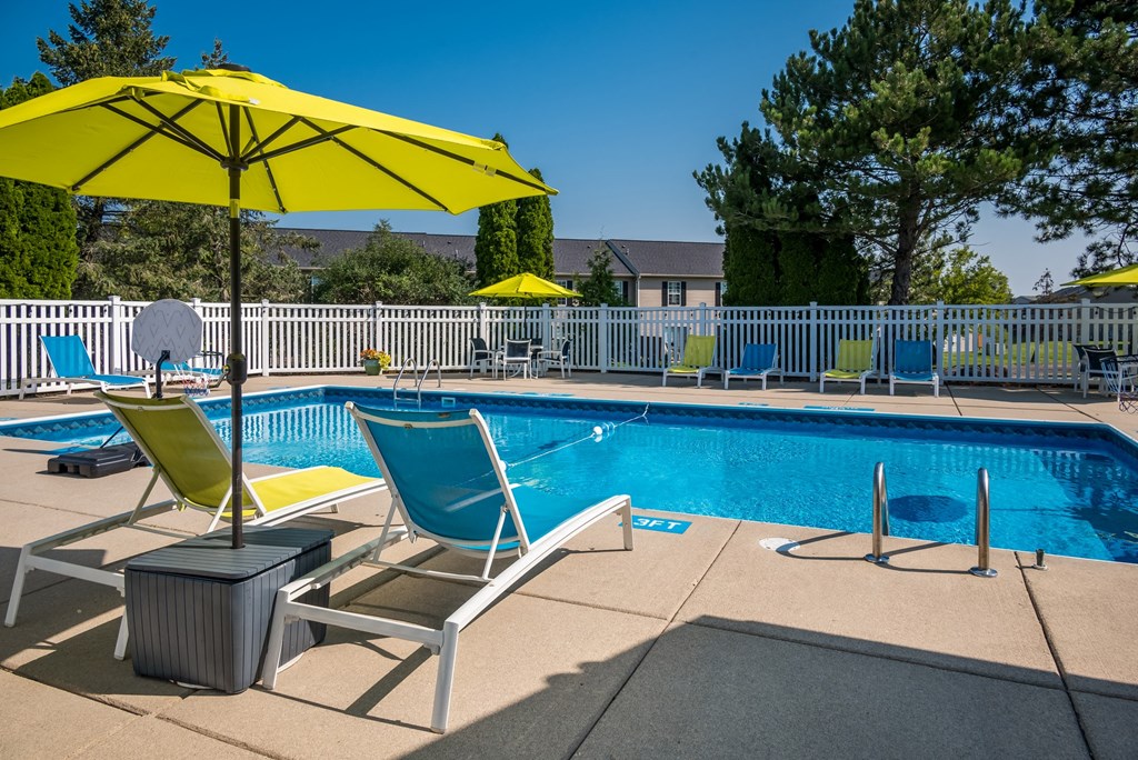 a swimming pool with two lounge chairs and an umbrella