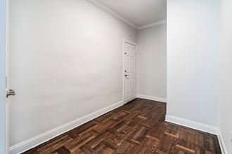 a bedroom with white walls and wood flooring and a door