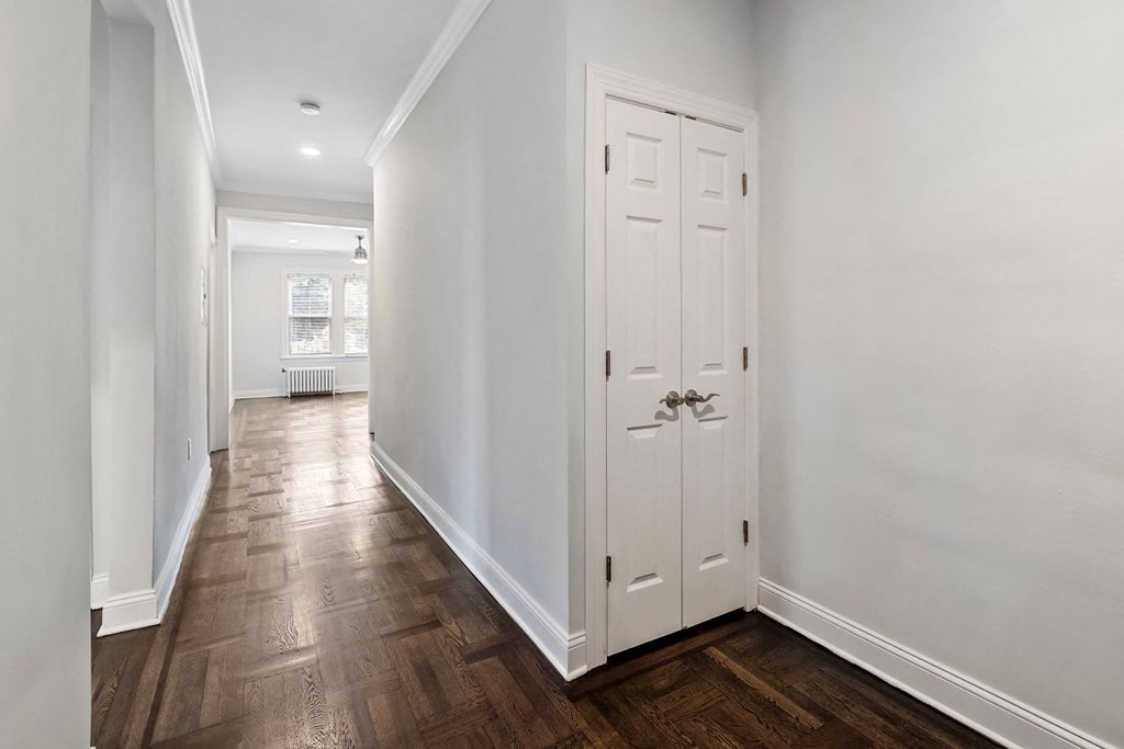 a hallway with two white closets and a wood floor