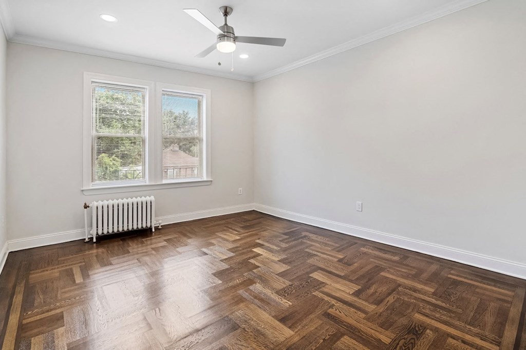 an empty living room with wood floors and a ceiling fan